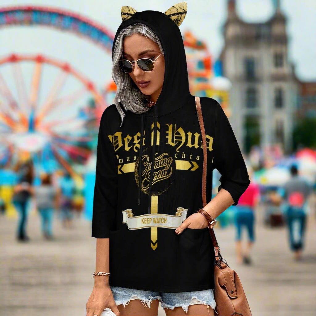 Person wearing a black hoodie with gold text and cat ears, holding a brown bag.