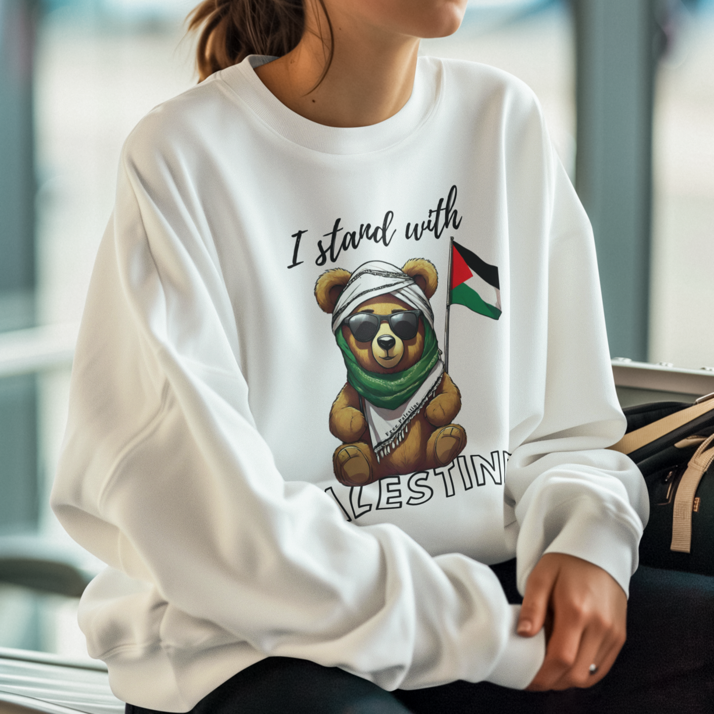 Woman wearing a white sweatshirt with a bear graphic and 'I stand with Palestine' text.