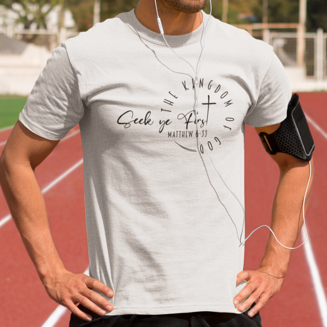 Man on a running track wearing a white t-shirt with text and earphones.