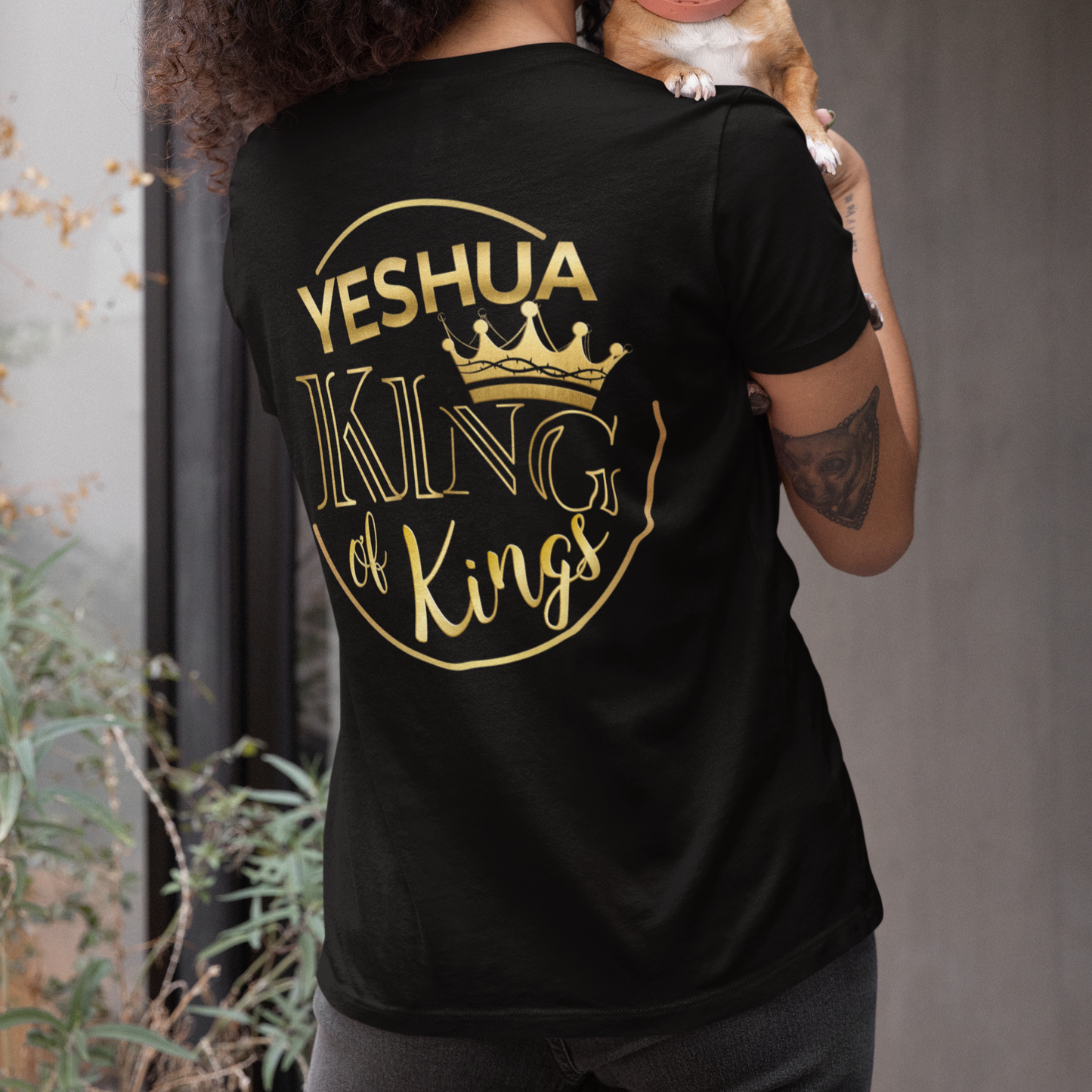 Person wearing a black t-shirt with 'Yeshua King of Kings' text, holding a small dog.