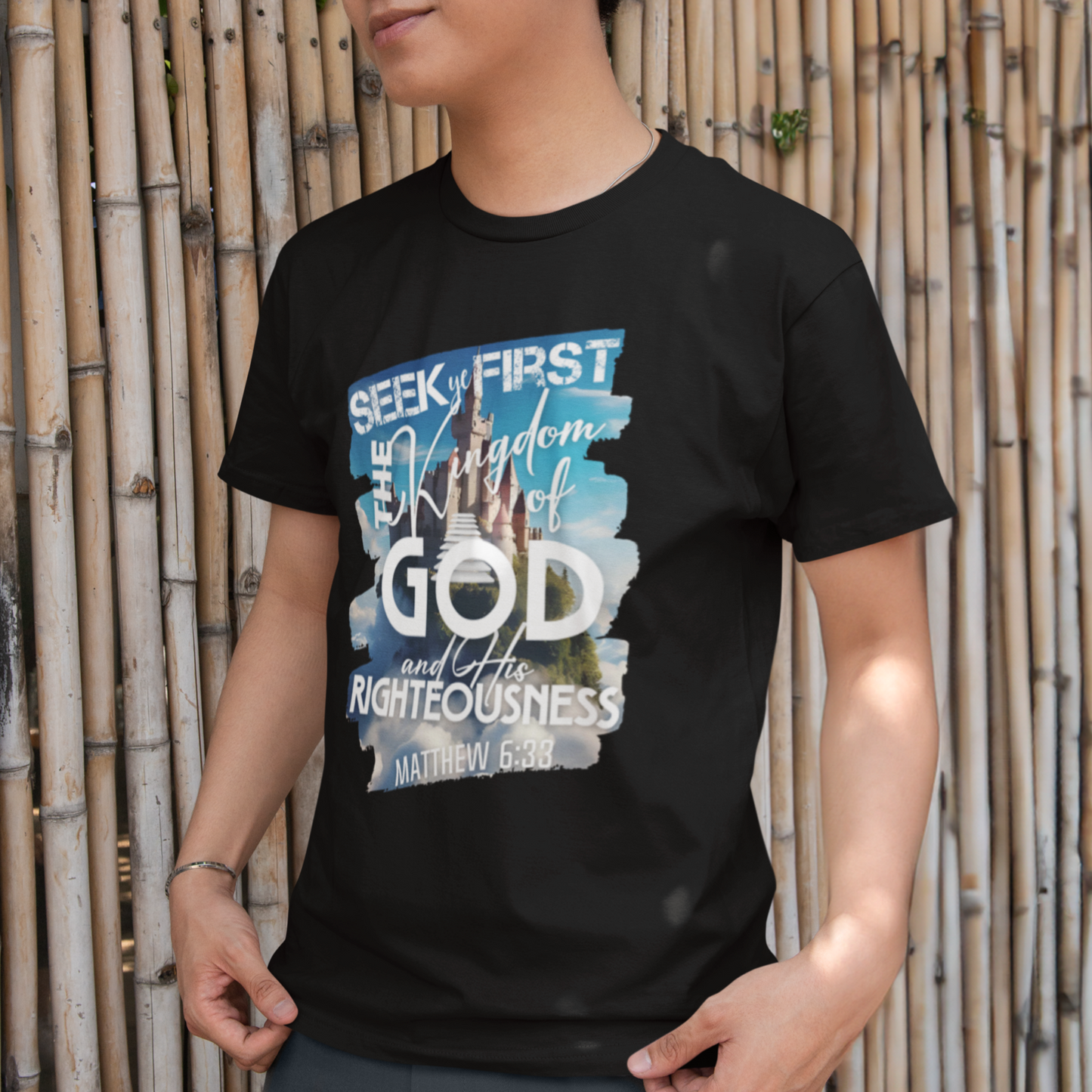 Person wearing a black t-shirt with a colorful graphic design against a bamboo background