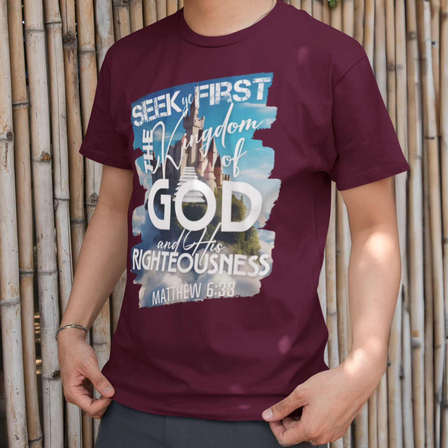 Person wearing a maroon t-shirt with a graphic design in front of a bamboo wall