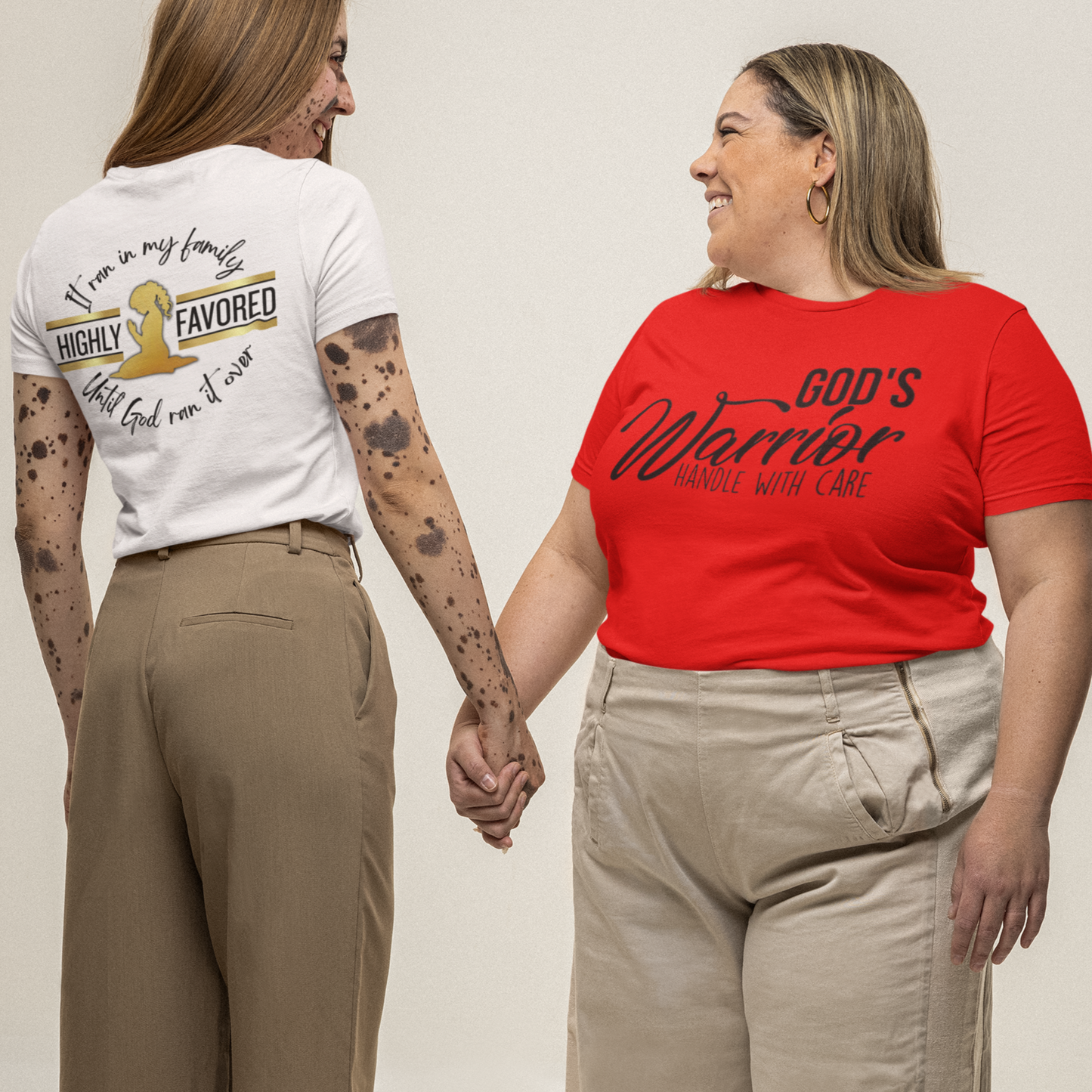 Two women holding hands, wearing t-shirts with text and graphics.