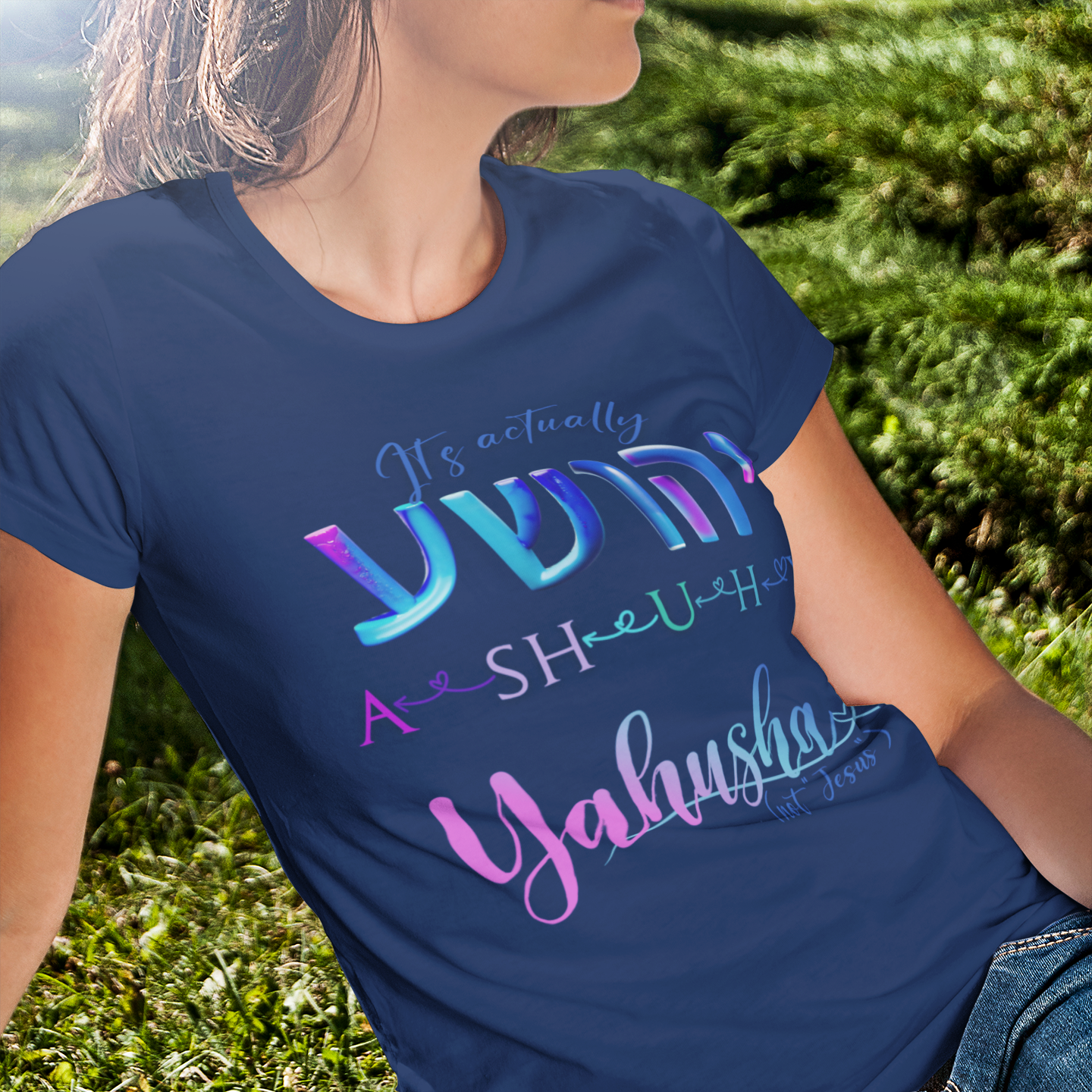 Person wearing a blue t-shirt with colorful text sitting on grass