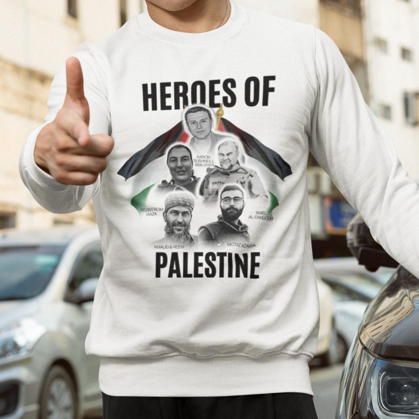 Person wearing a white sweatshirt with 'Heroes of Palestine' graphic, standing on a street.