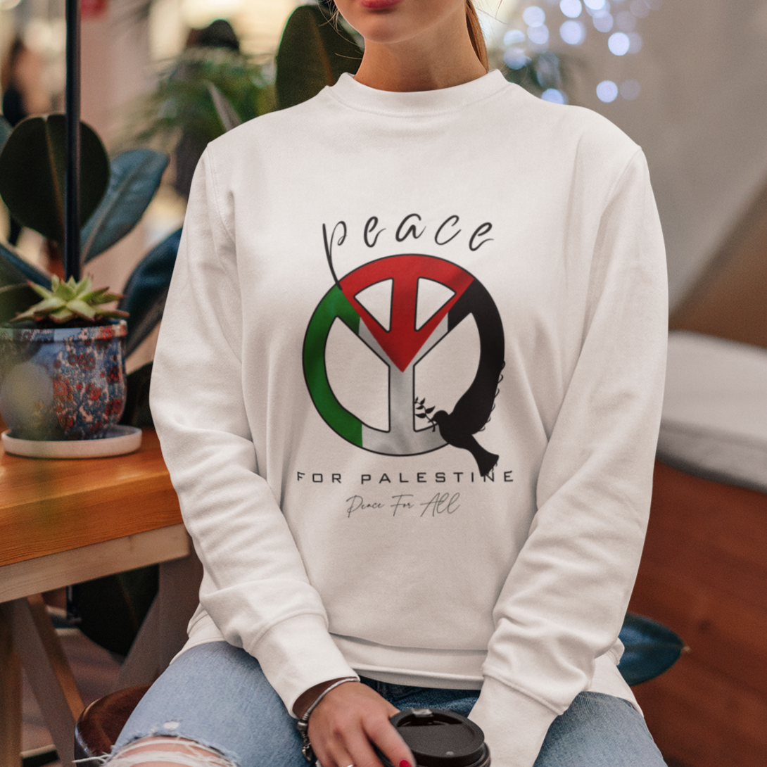 Woman wearing a white sweatshirt with a peace symbol design, sitting in a cafe.