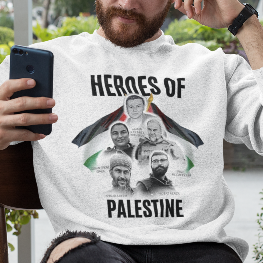 Man wearing a sweatshirt with 'Heroes of Palestine' graphic, sitting outdoors.
