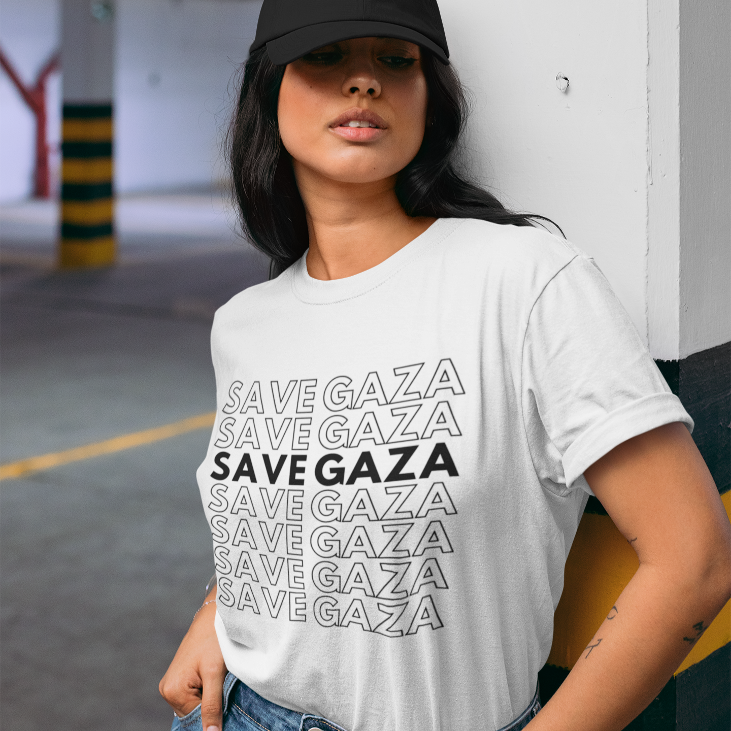 Person wearing a white t-shirt with 'SAVE GAZA' text in a parking garage.