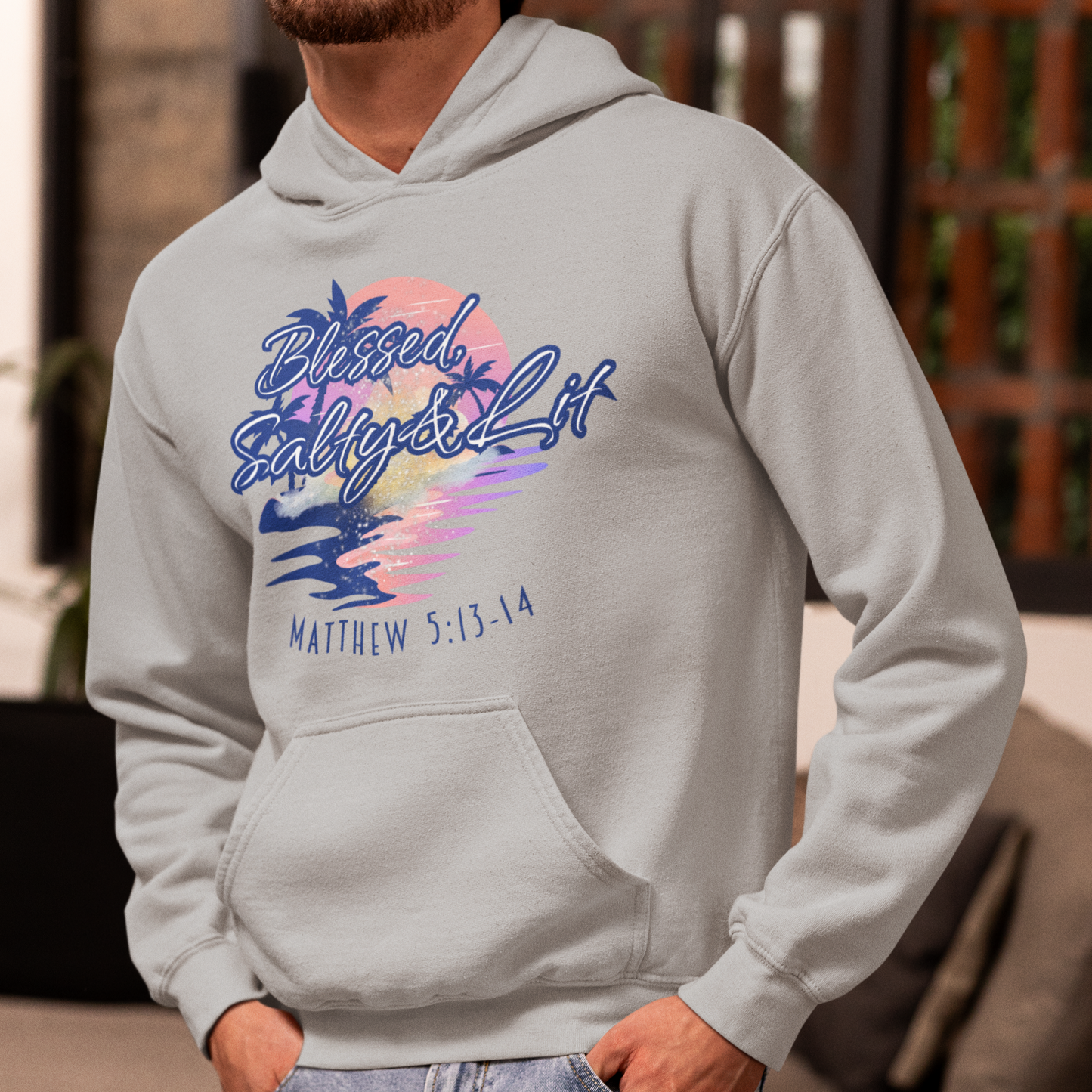 Person wearing a gray hoodie with colorful text and design, standing indoors.
