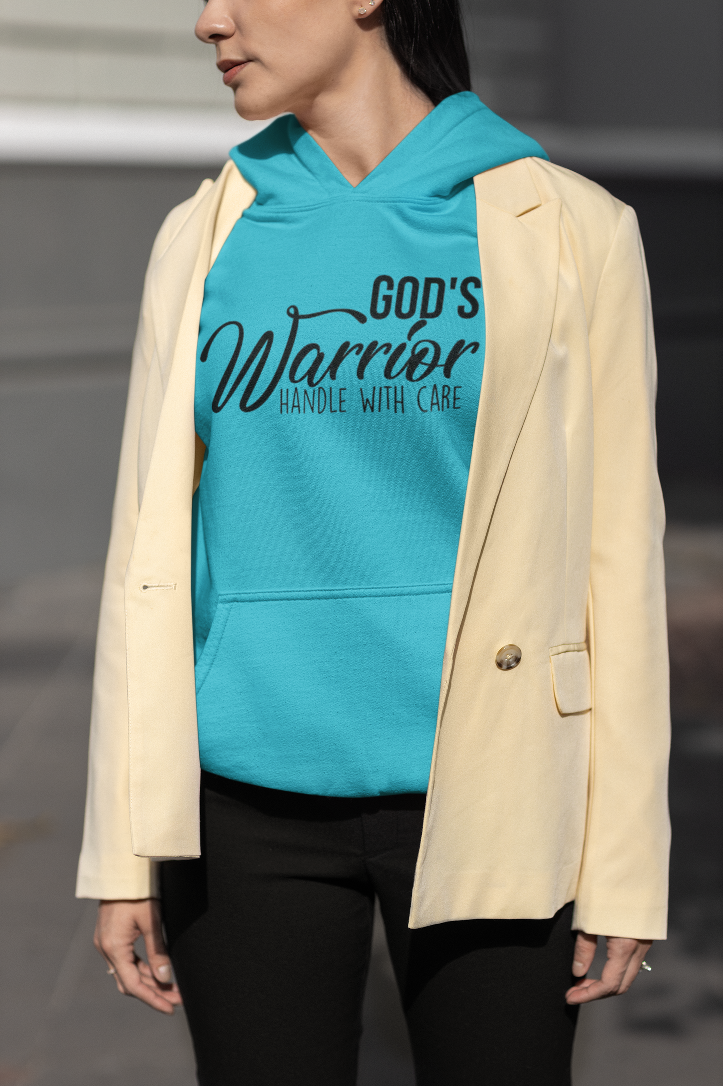 Person wearing a turquoise hoodie with 'God's Warrior Handle with Care' text, paired with a beige blazer.