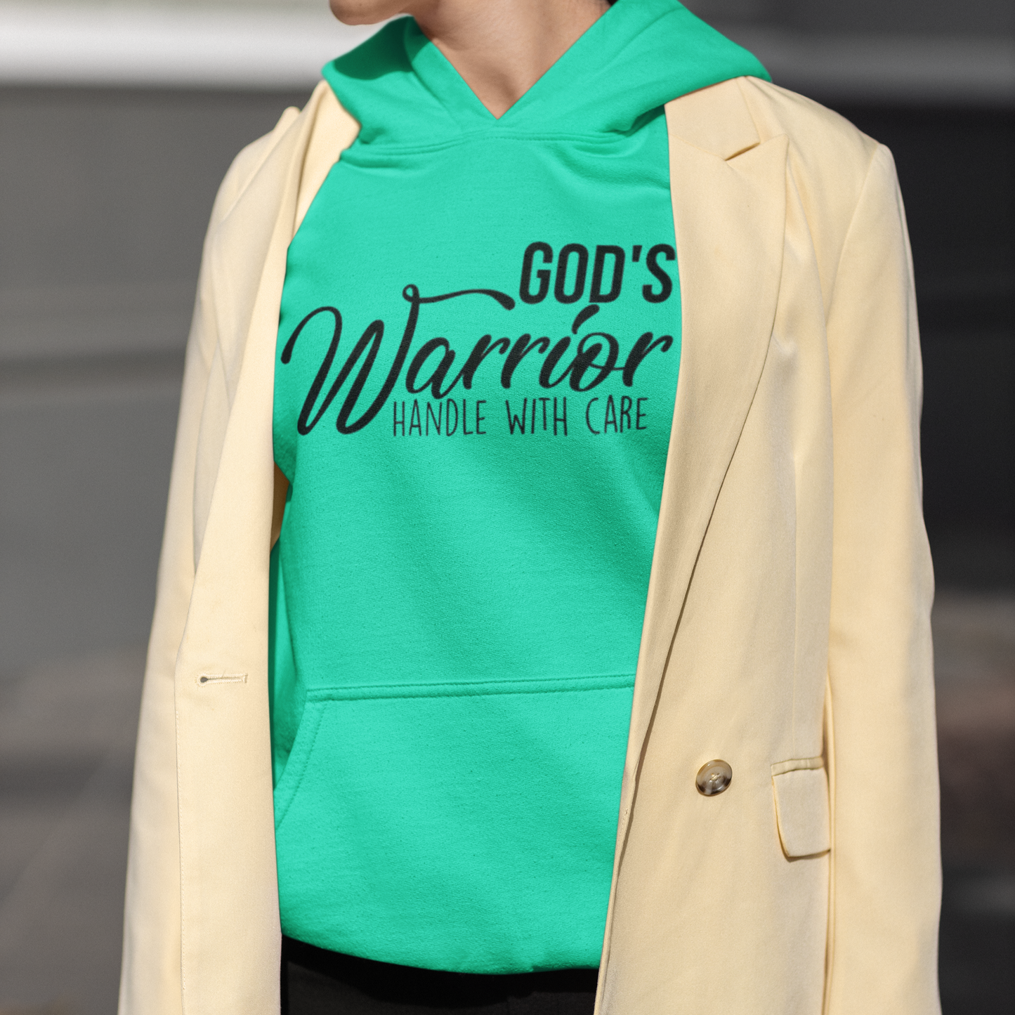 Person wearing a green hoodie with text and a beige blazer.