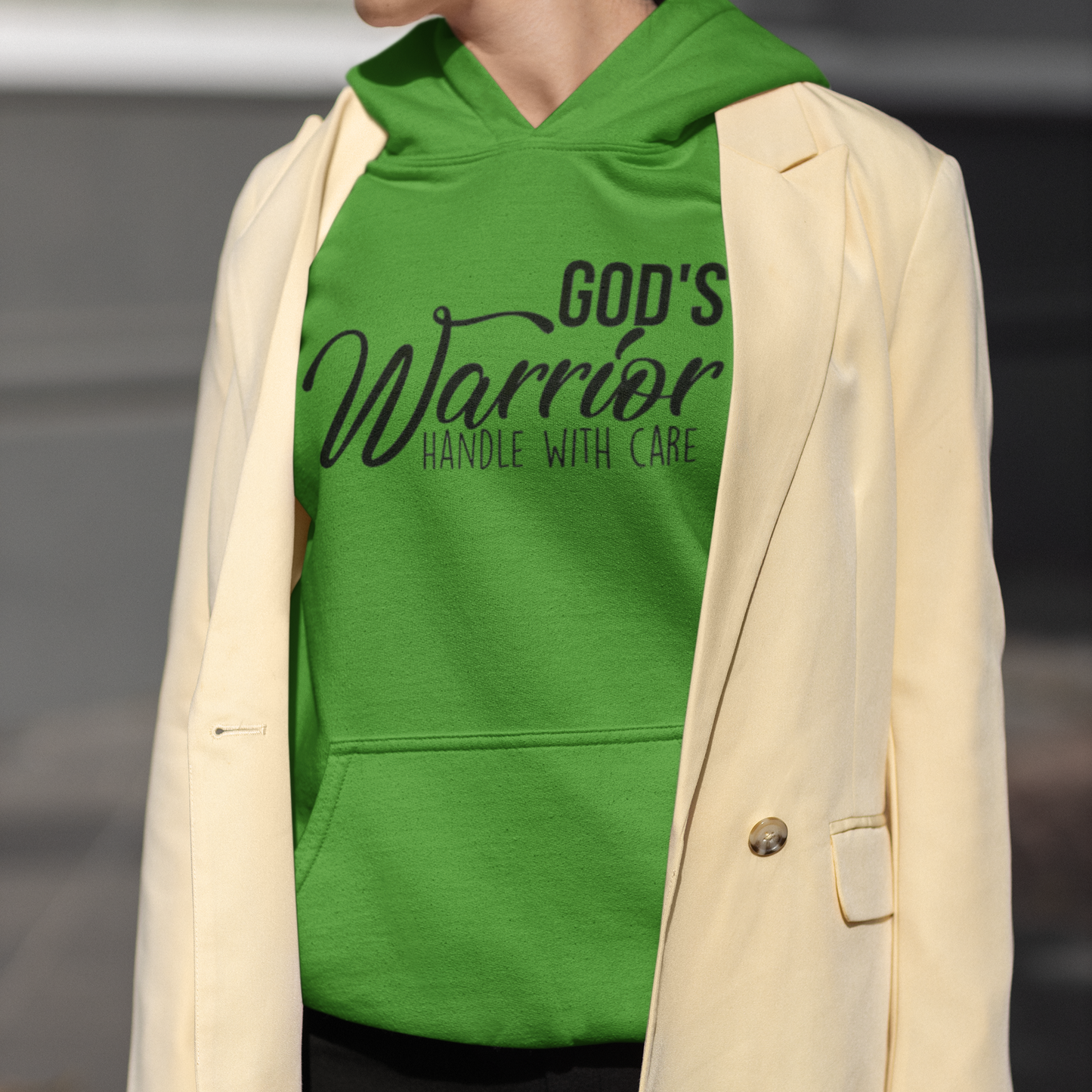 Person wearing a green hoodie with text and a beige blazer.