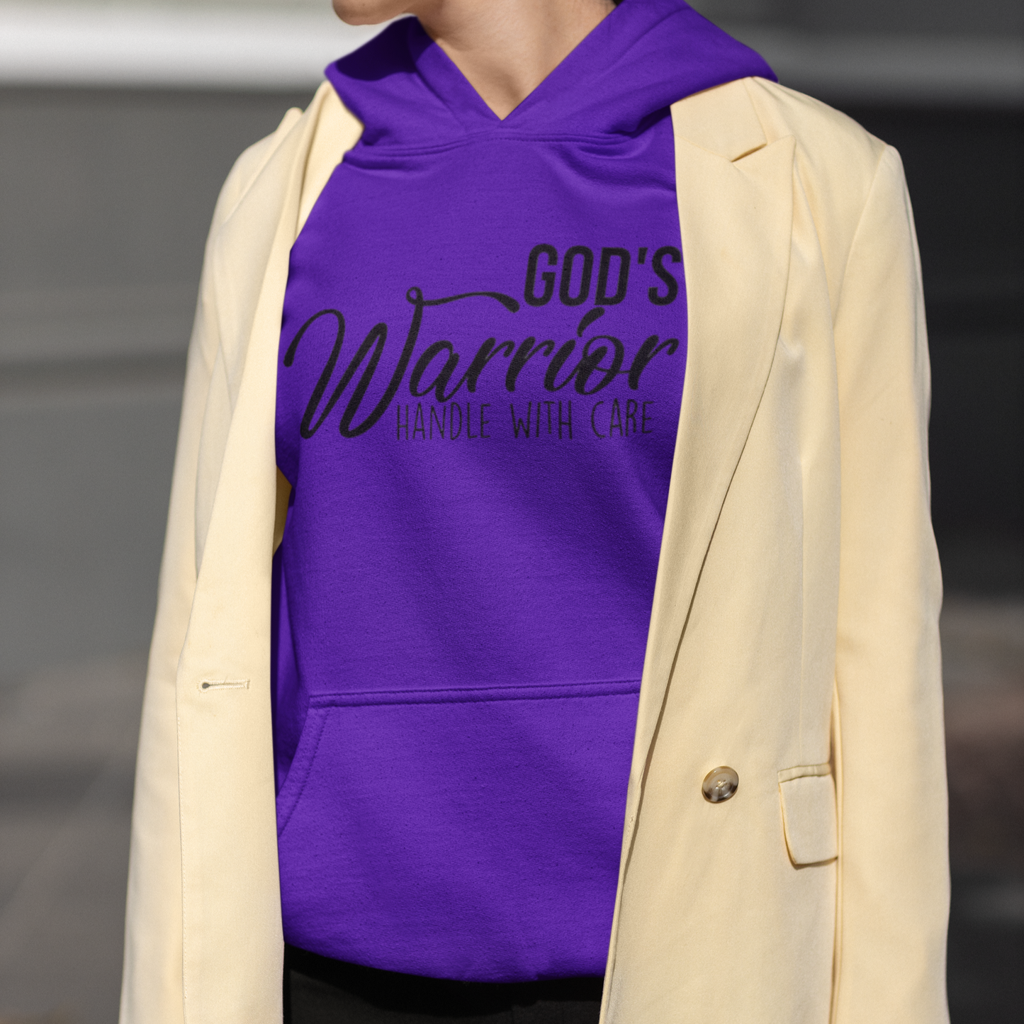 Person wearing a purple hoodie with text and a beige blazer.
