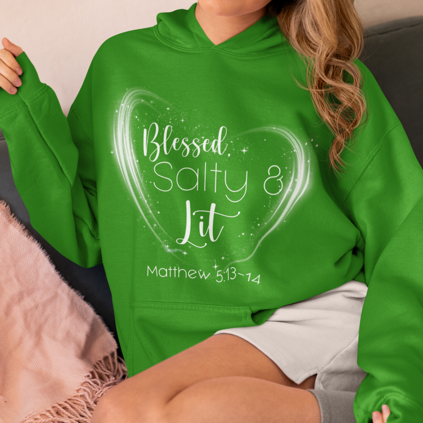 Person wearing a green hoodie with text design sitting on a couch.