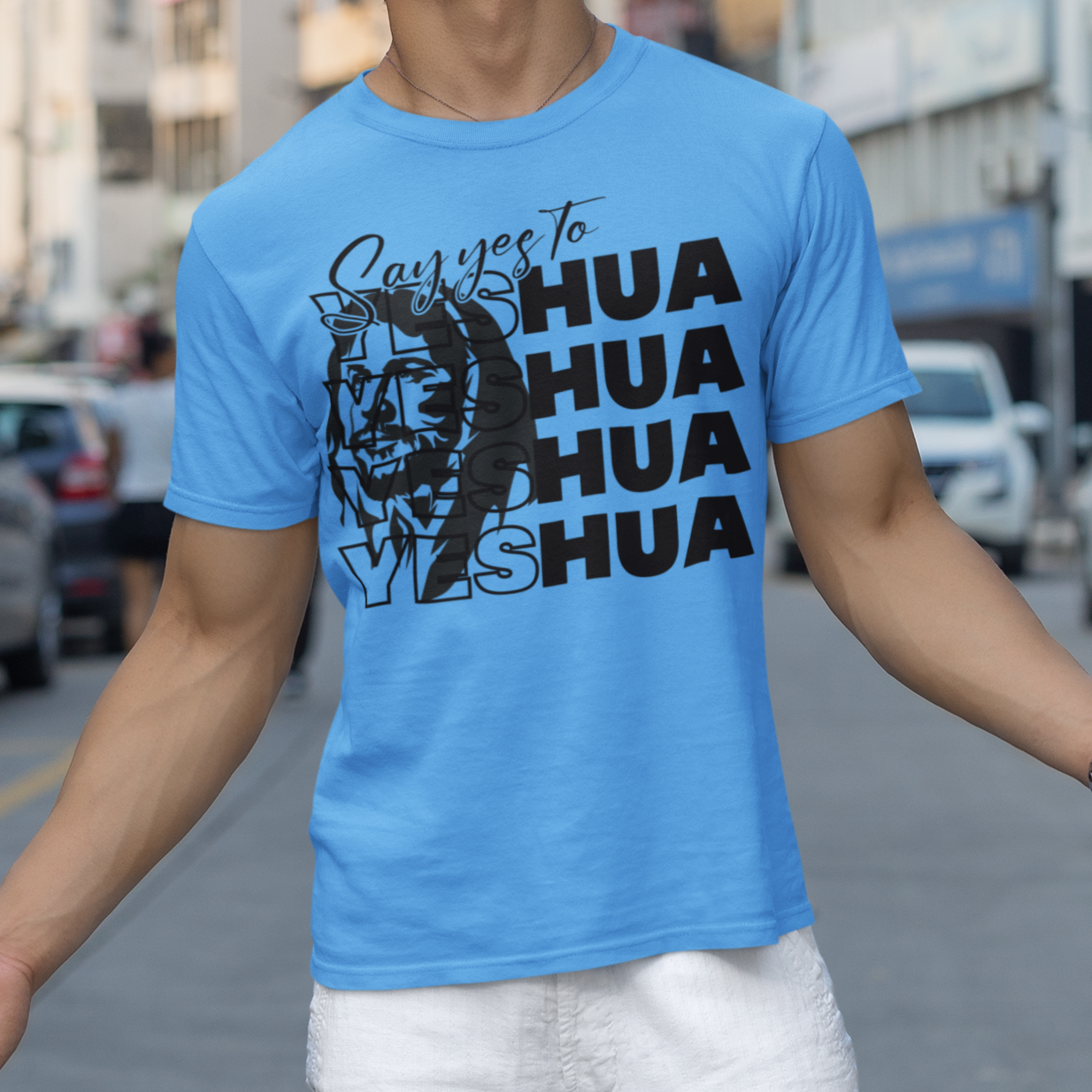 Person wearing a blue t-shirt with text and graphics on a city street.