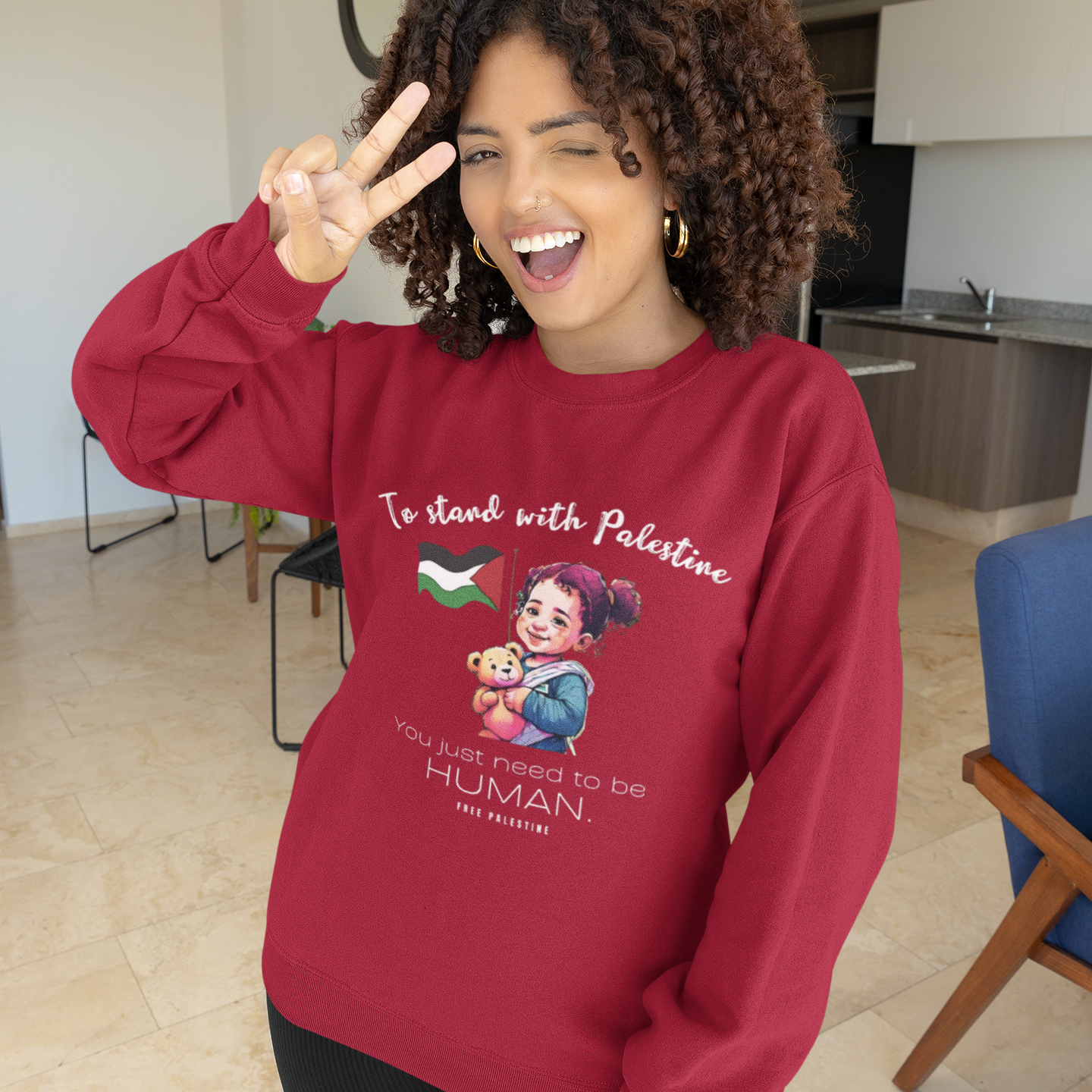 Person wearing a red sweatshirt with a graphic and text, standing in a modern indoor setting.