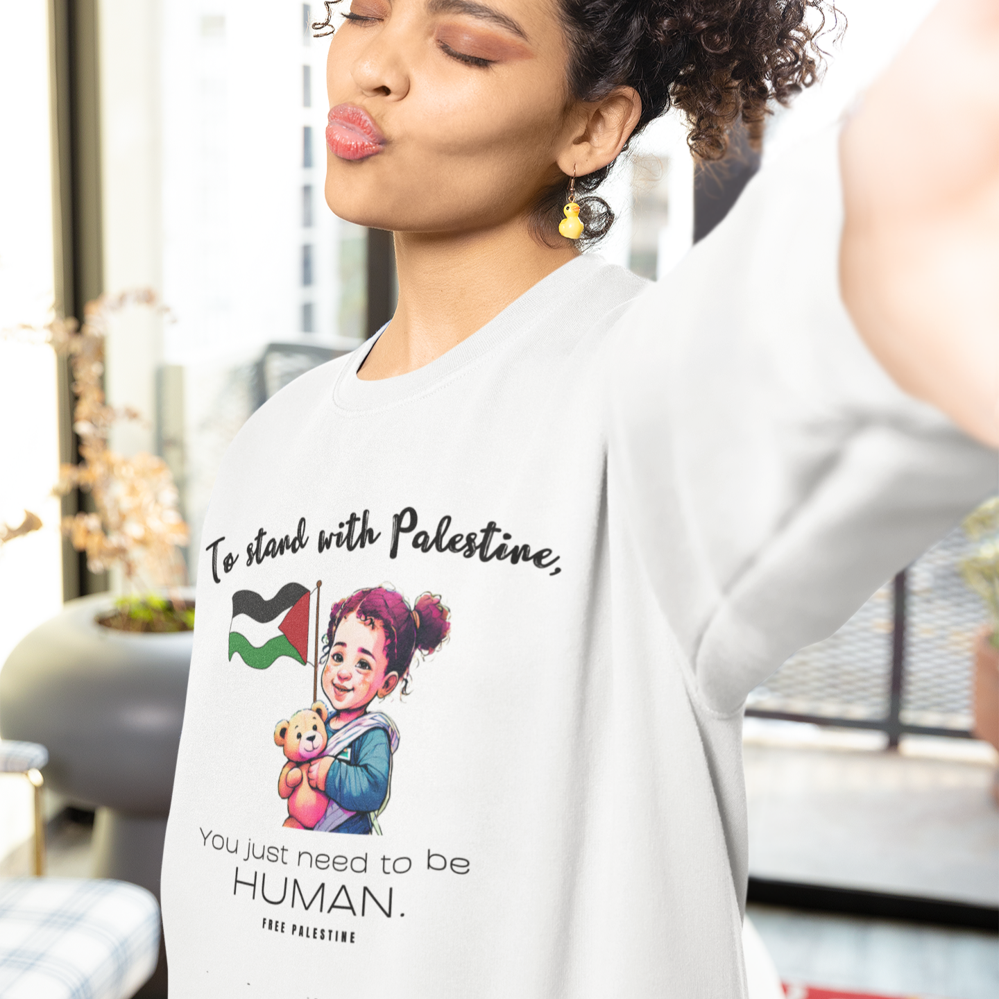 Woman wearing a shirt with a graphic and text, standing in an indoor setting.