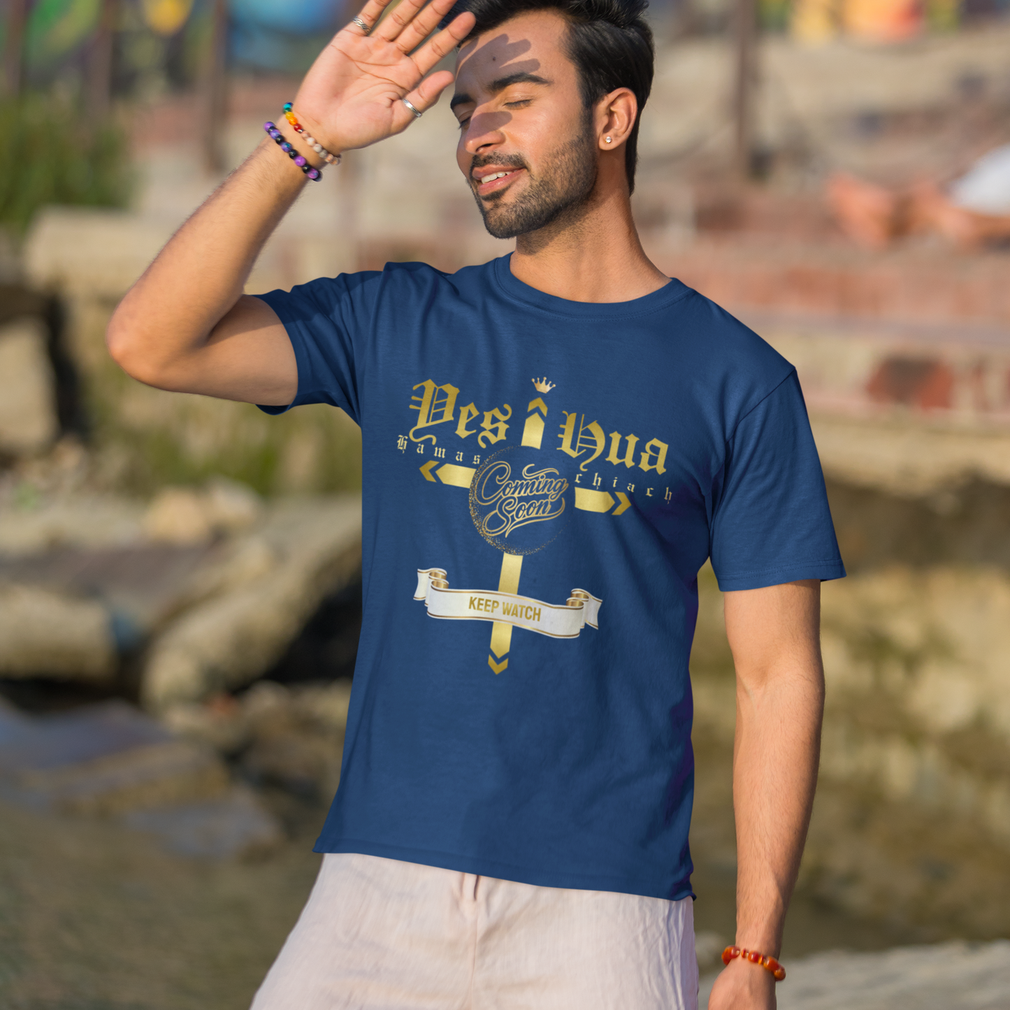 Man wearing a blue t-shirt with text and graphics, standing outdoors with a colorful mural in the background.