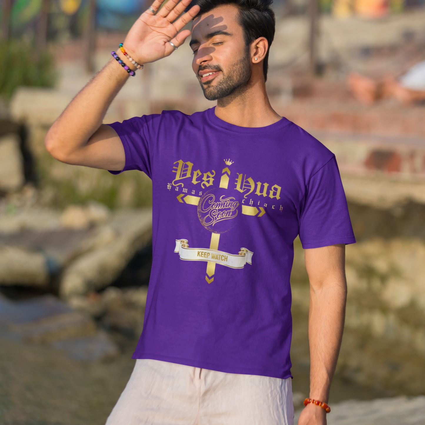 Man wearing a purple t-shirt with text, standing outdoors with a colorful mural in the background.
