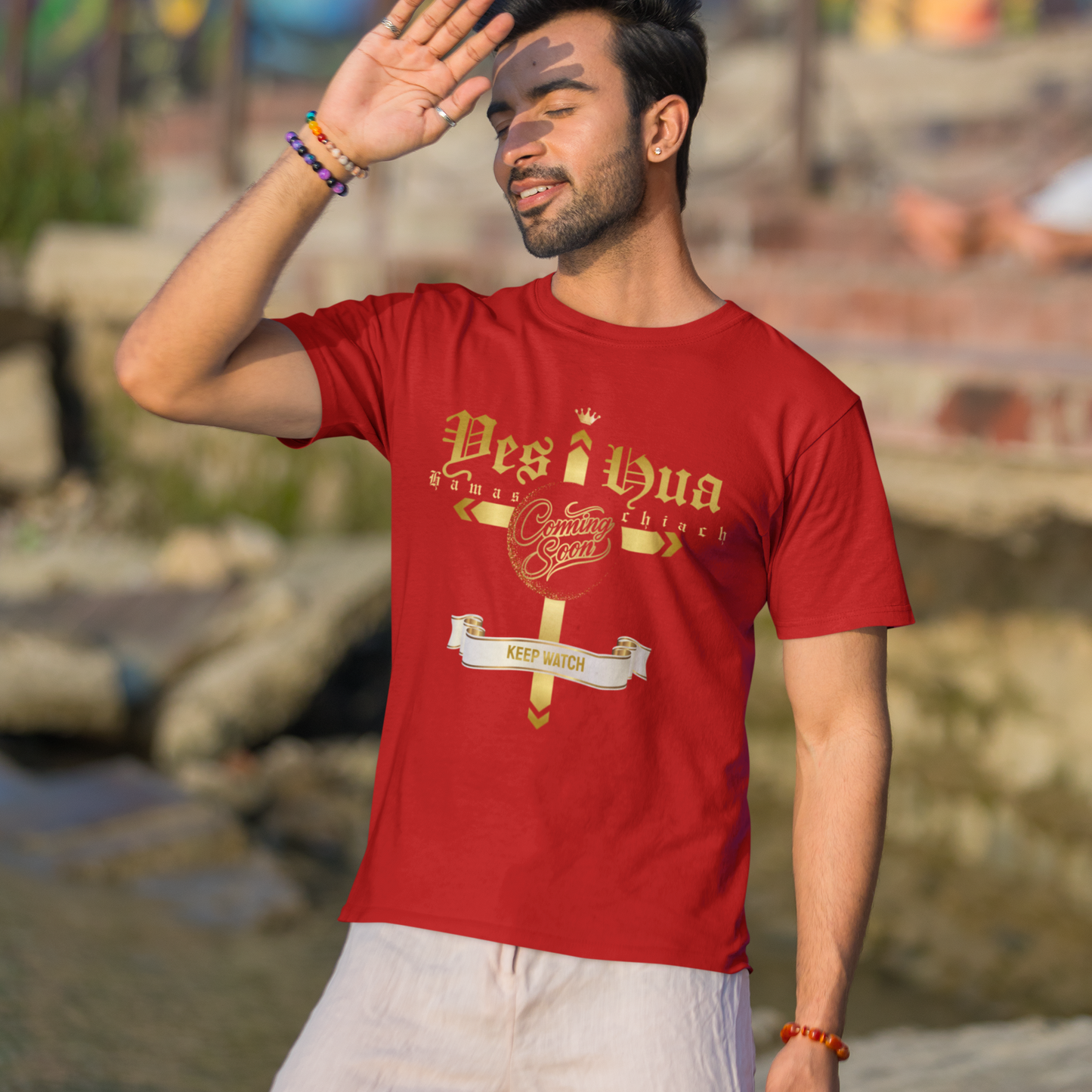 Man wearing a red t-shirt with text, standing outdoors with a colorful mural in the background.