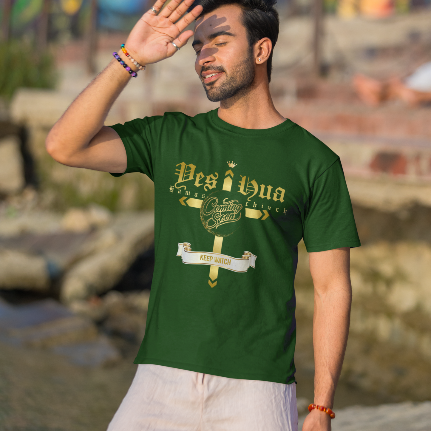Man wearing a green t-shirt with text, standing outdoors with a colorful mural in the background.