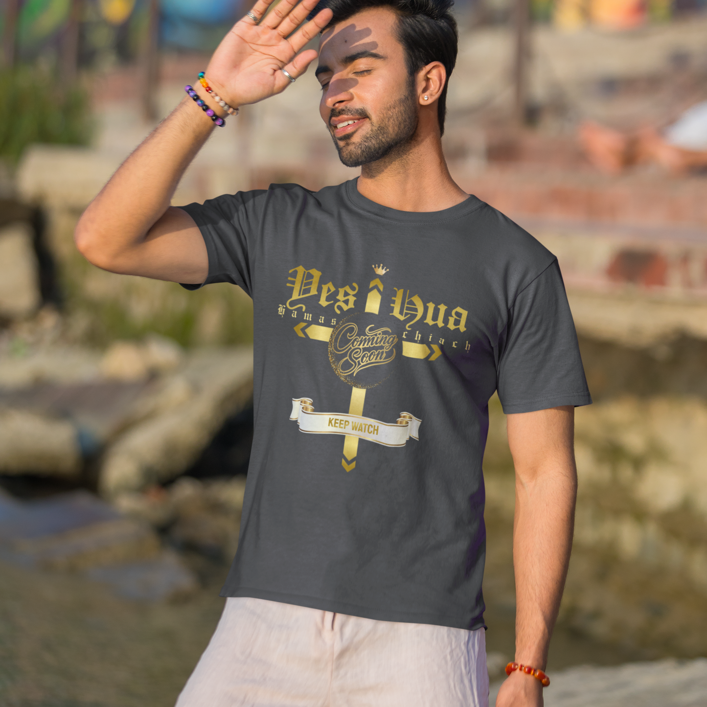 Man wearing a dark gray t-shirt with text and graphics, standing outdoors with a colorful mural in the background.