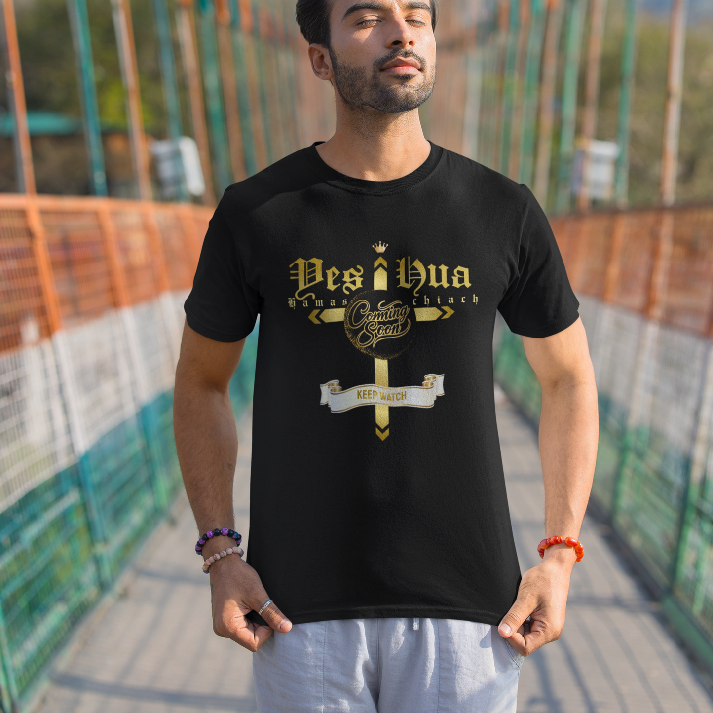 Man wearing a black t-shirt with 'Desi Bua' design on a suspension bridge