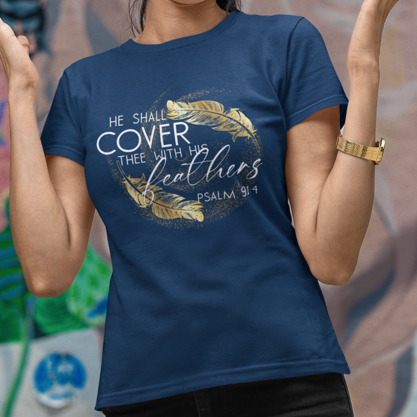 Woman wearing a blue t-shirt with text and design, standing in front of a colorful mural.