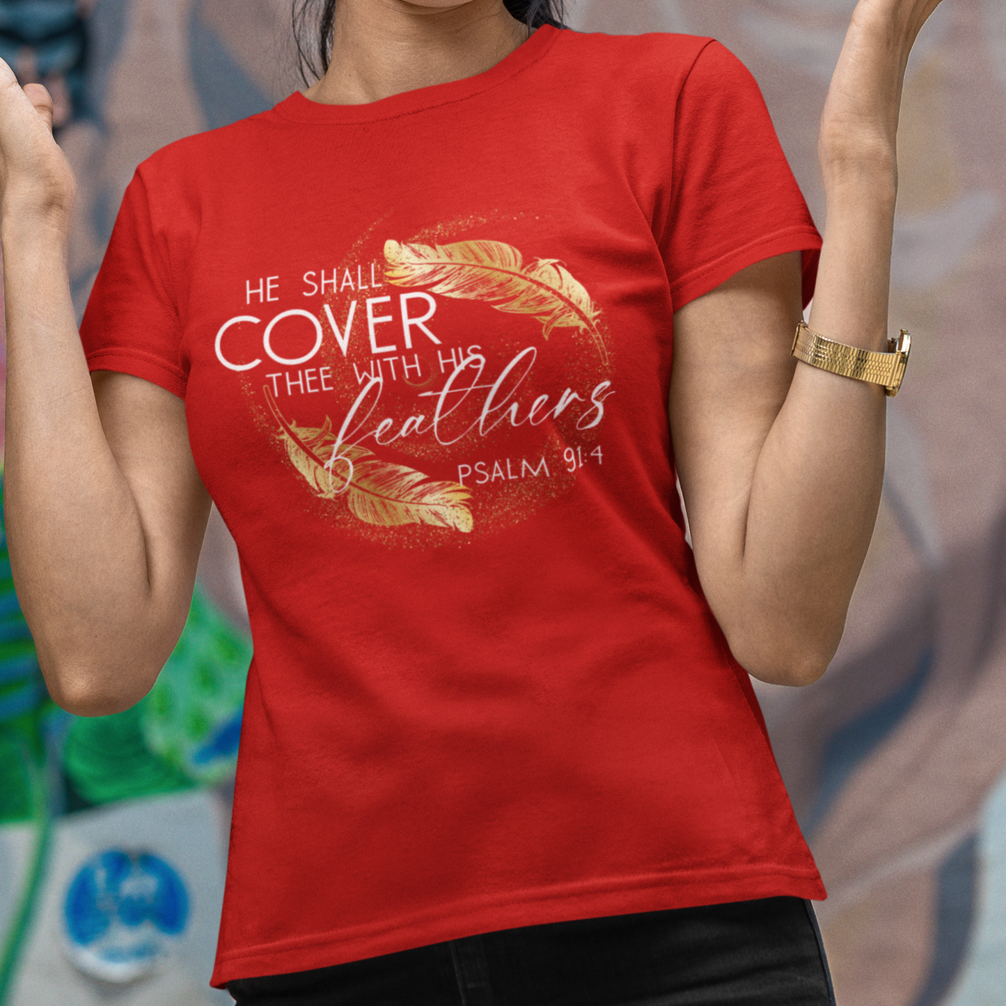 Woman wearing a red t-shirt with text and design, standing in front of a colorful mural.