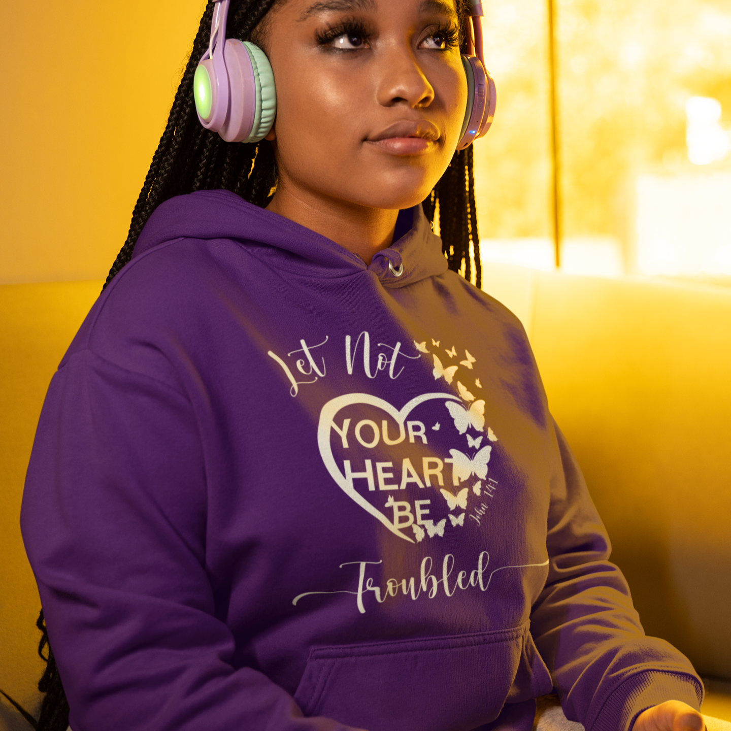 Person wearing a purple hoodie with text and graphics, sitting on a yellow couch.