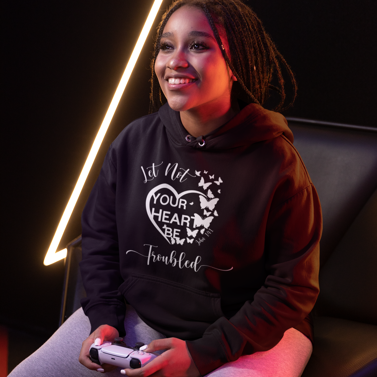 Woman playing video games wearing a hoodie with a heart design and text.