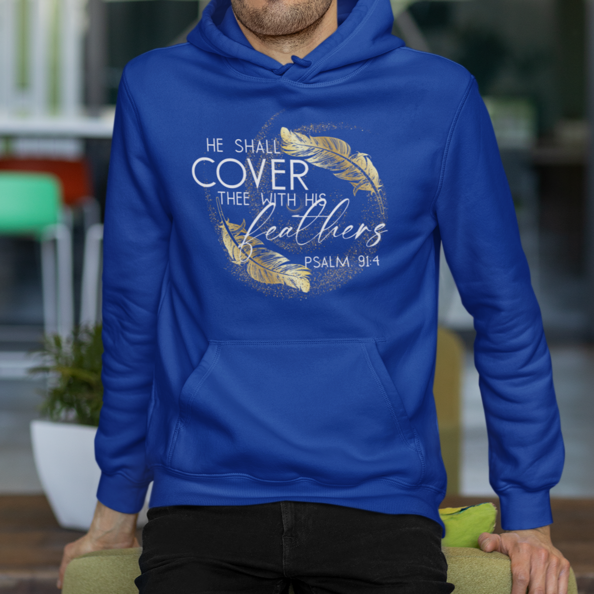Man wearing a blue hoodie with text and design, sitting on a chair indoors.