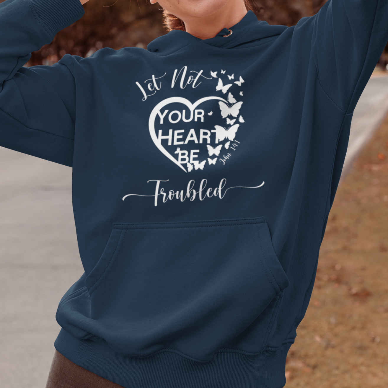 Woman wearing a navy blue hoodie with a motivational quote, standing outdoors.