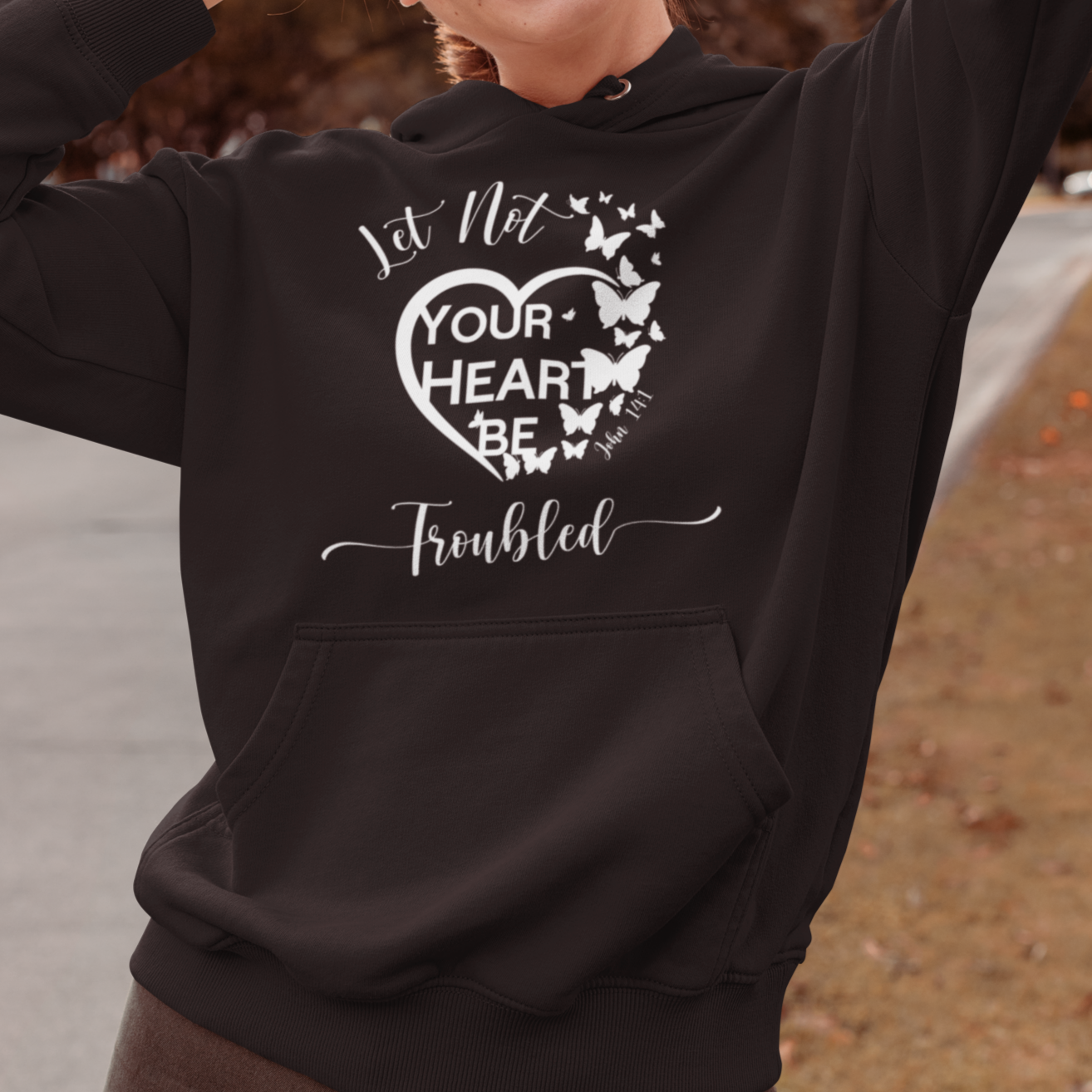 Woman wearing a black hoodie with a heart design and text, standing outdoors.