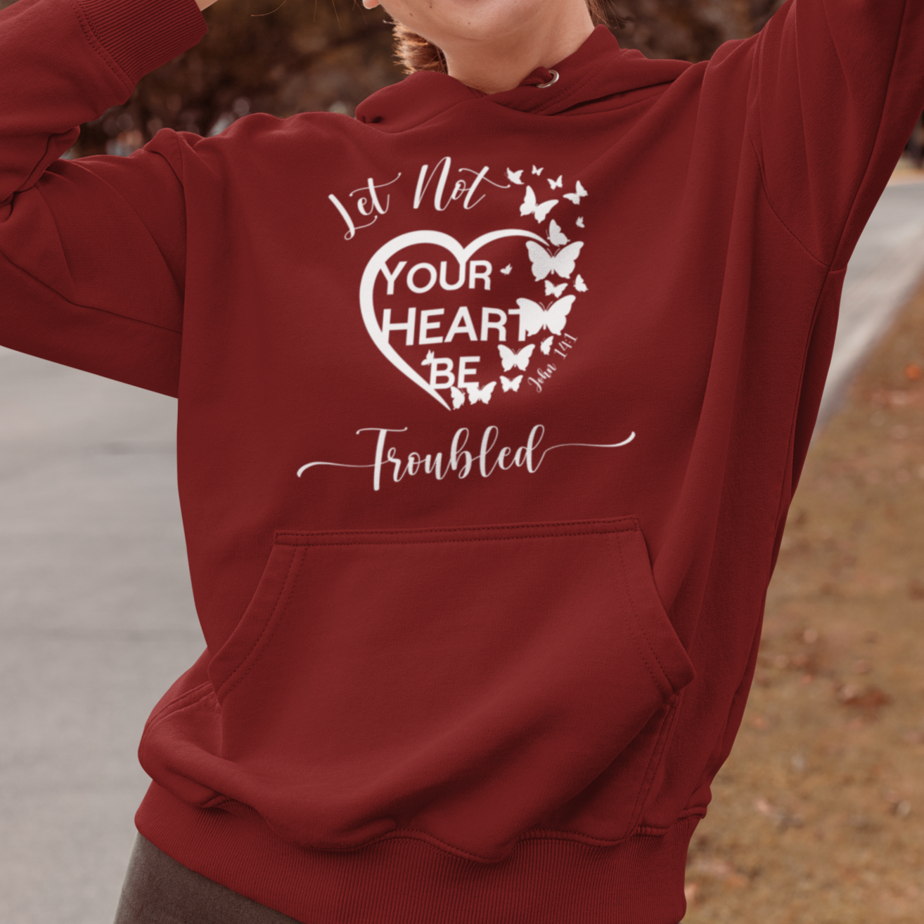 Person wearing a red hoodie with a heart design and text, outdoors.