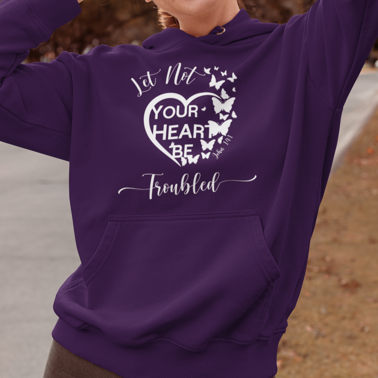 Person wearing a purple hoodie with a heart design and text, standing outdoors.