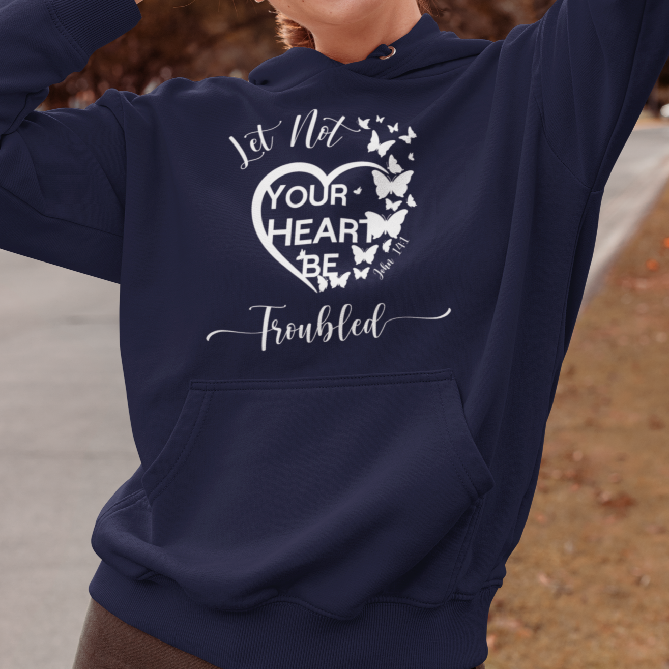Woman wearing a navy blue hoodie with a motivational quote, standing outdoors.