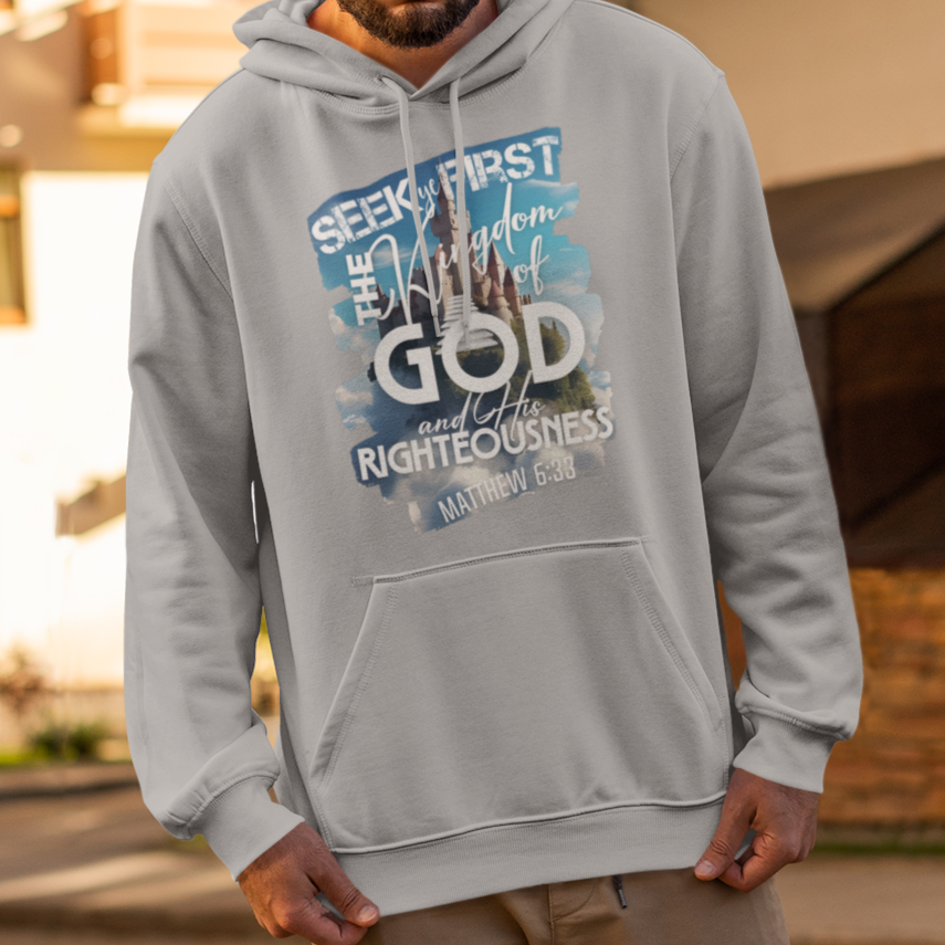 Man wearing a gray hoodie with text, standing on a street with buildings in the background