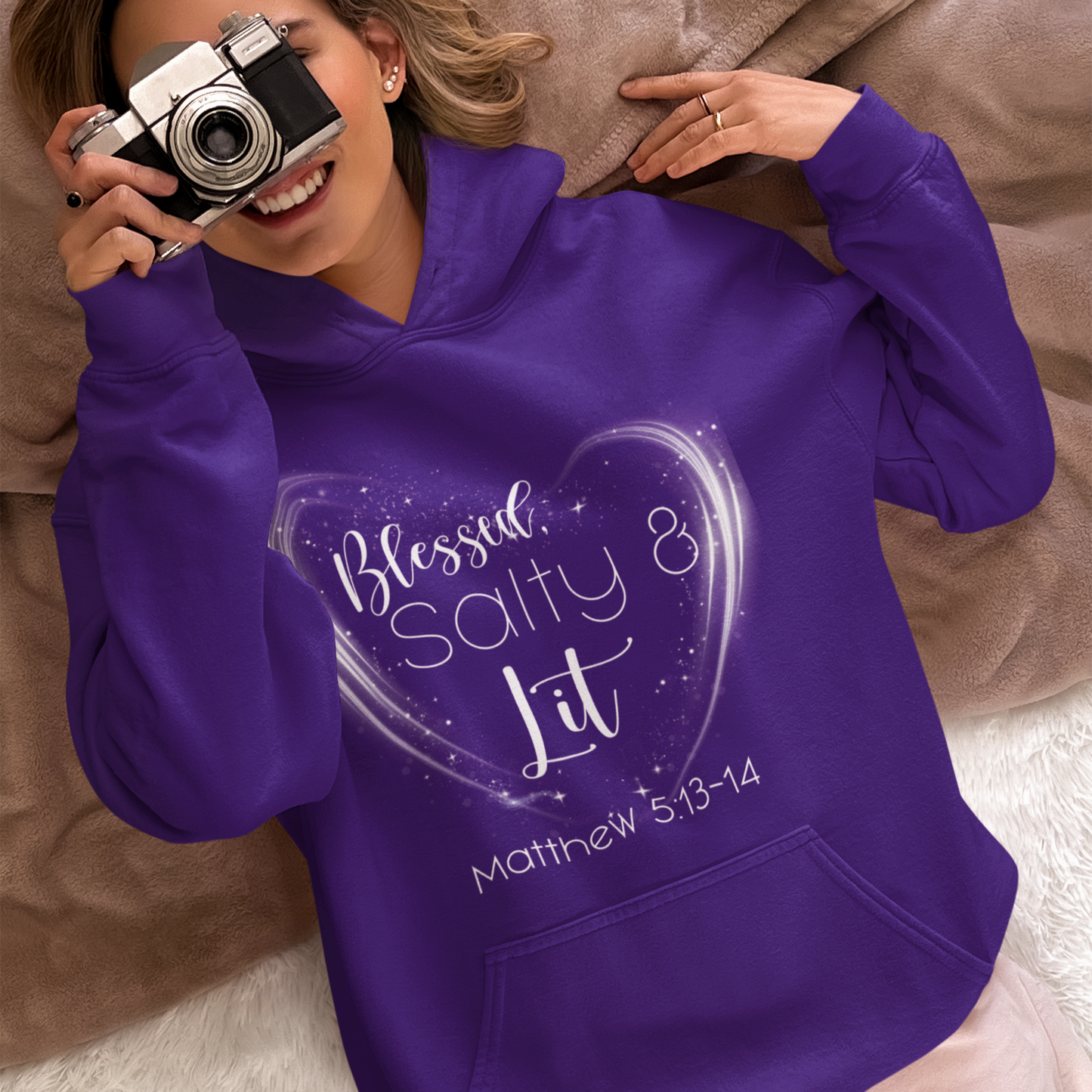 Person wearing a purple hoodie with text, holding a camera.