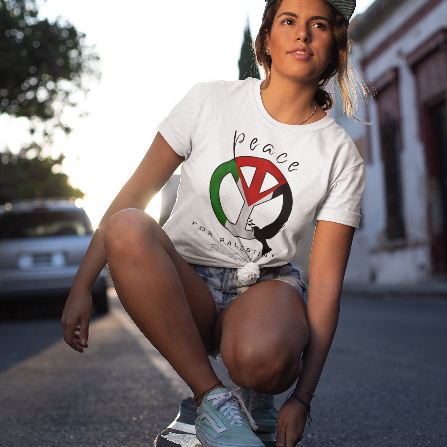 Person skateboarding on a street wearing a white t-shirt with a peace symbol design.