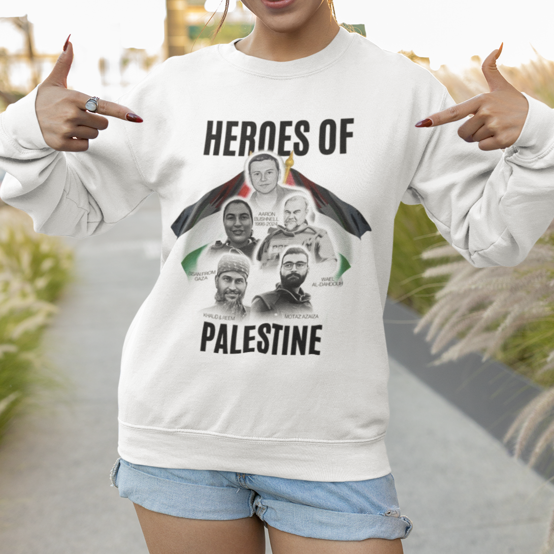 Person wearing a white sweatshirt with 'Heroes of Palestine' graphic, standing outdoors.