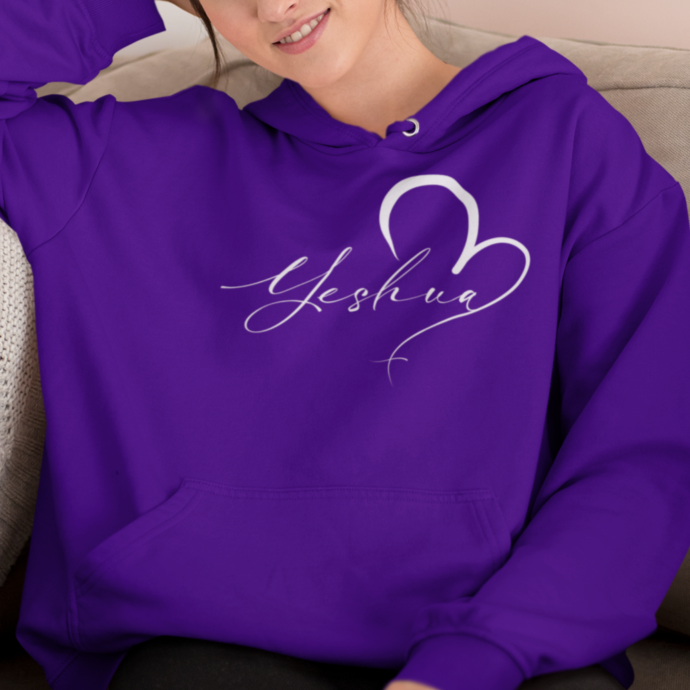 Woman wearing a purple hoodie with 'Yeshua' design sitting on a couch.