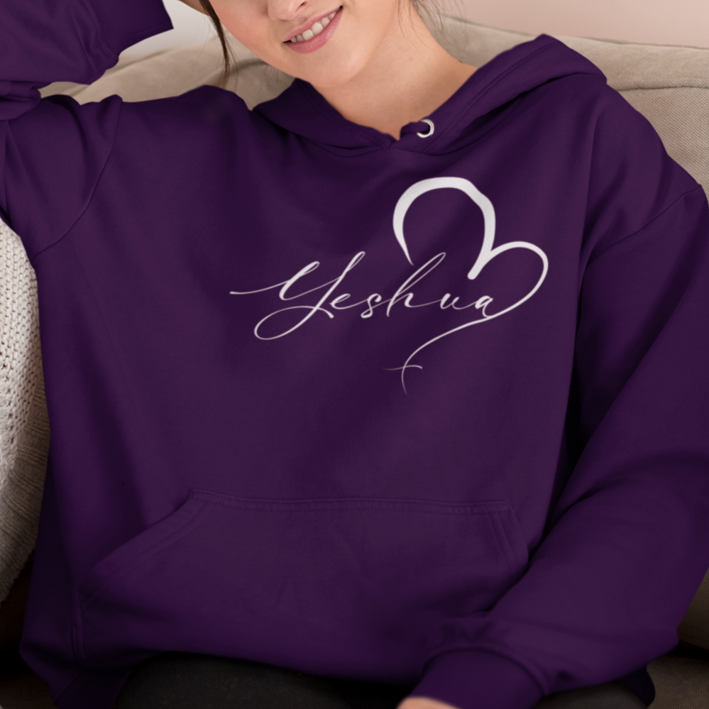 Woman wearing a purple hoodie with 'Yeshua' design, sitting on a couch.