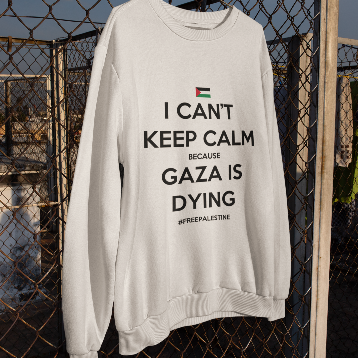 White sweatshirt with a message about Gaza hanging on a chain-link fence.