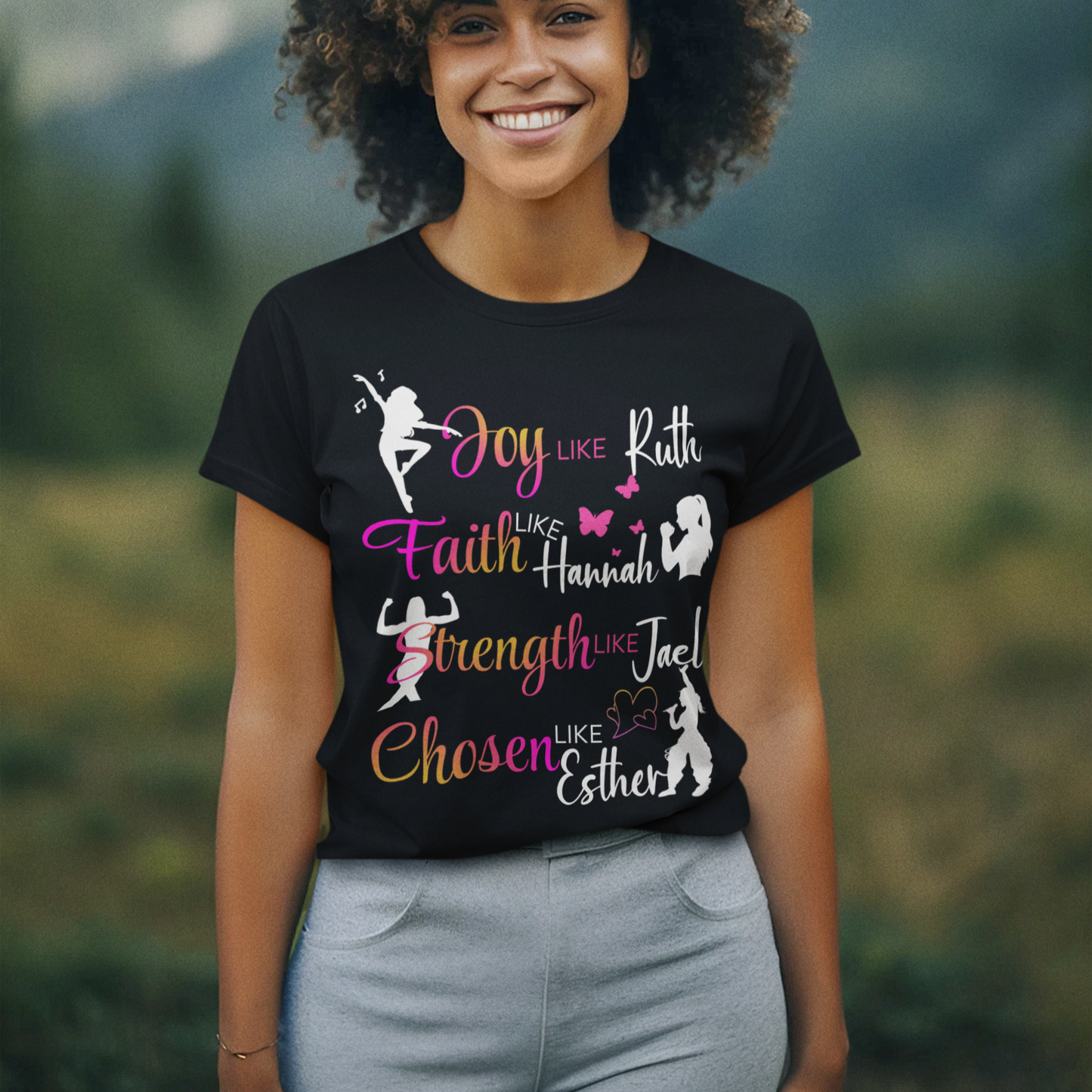 Person wearing a black t-shirt with colorful text and graphics against a mountainous background