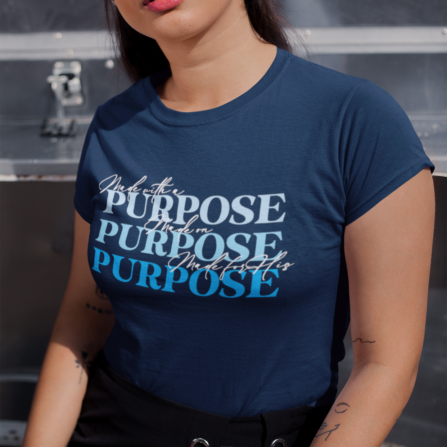 Woman wearing a blue t-shirt with motivational text, standing against a dark background.