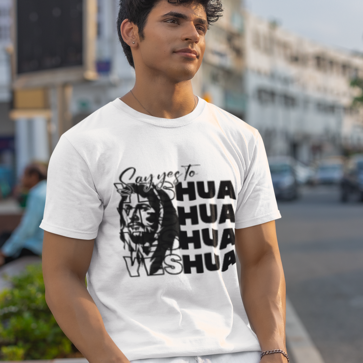 Man wearing a white t-shirt with black graphics and text, standing on a street.