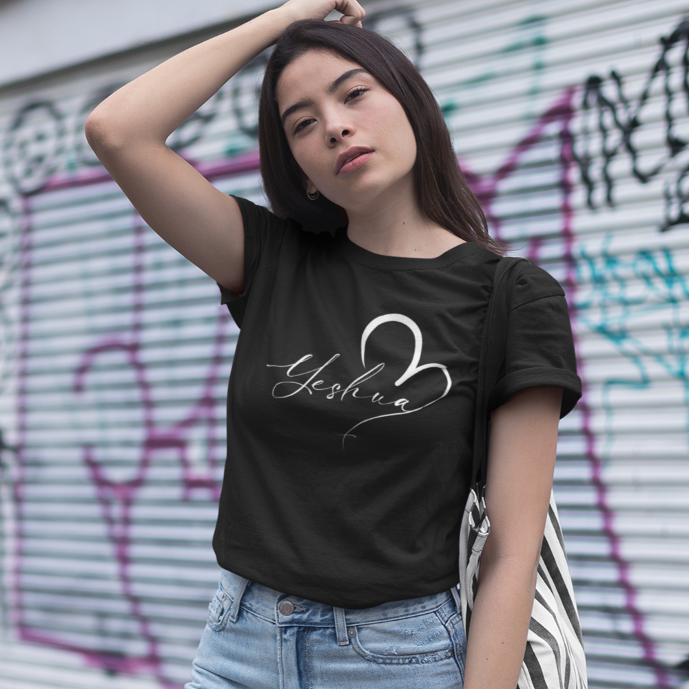 Woman wearing a black t-shirt with a logo and light blue jeans in front of a graffiti-covered wall.