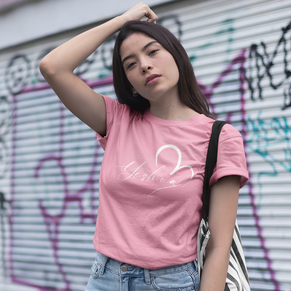 Woman wearing a pink t-shirt with a graphic design, standing in front of a graffiti-covered wall.