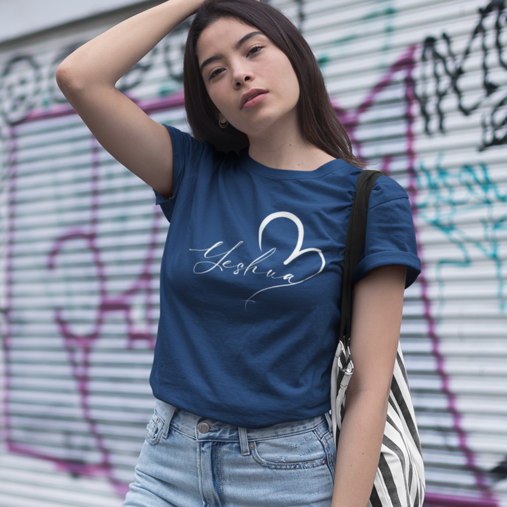 Woman wearing a blue t-shirt with a graphic design, standing in front of a graffiti-covered wall.